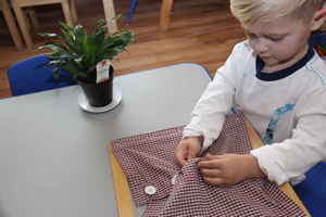 child learning to button shirt at montessori school - plano, tx