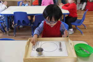 toddler setting the table at Kidz Camp Montessori School - Plano, TX