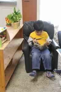 Young elementary boy reading independently at Kidz Camp Montessori School - Plano, TX